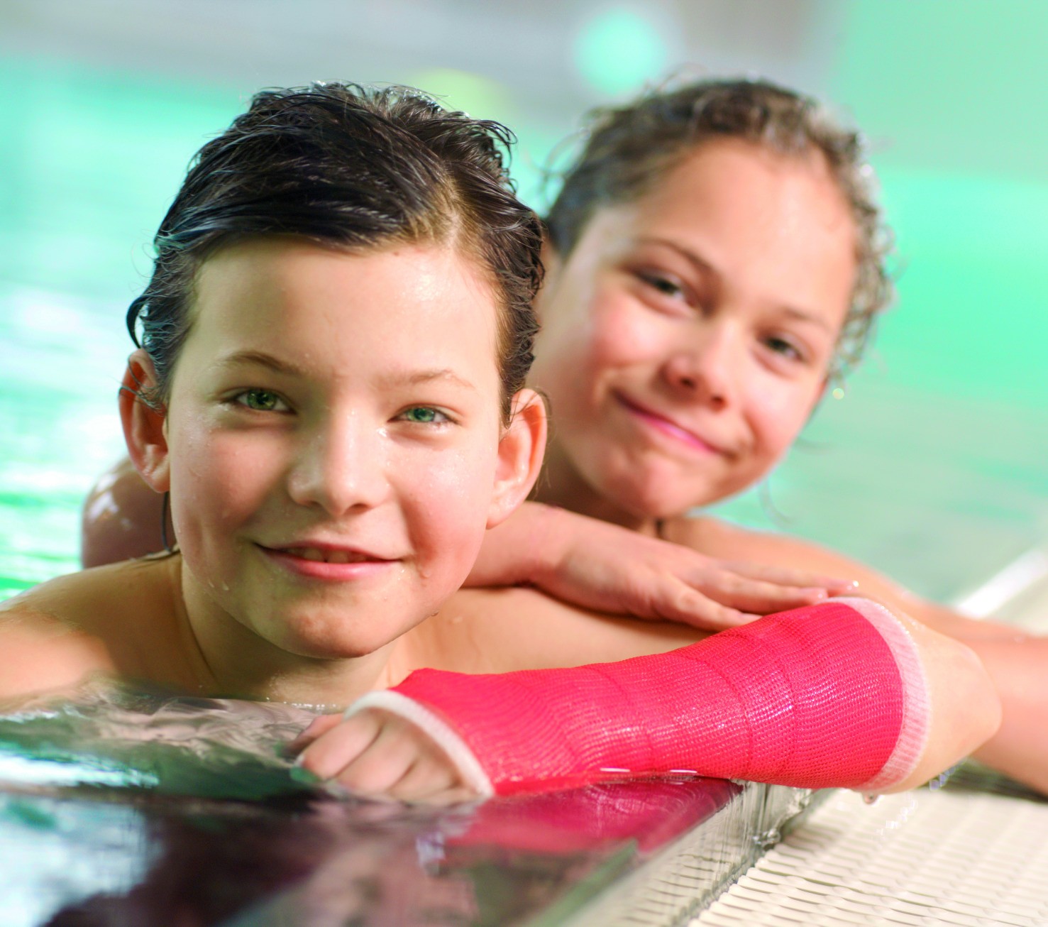Zwei Kinder im Schwimmbad, eines mit Gips am Arm